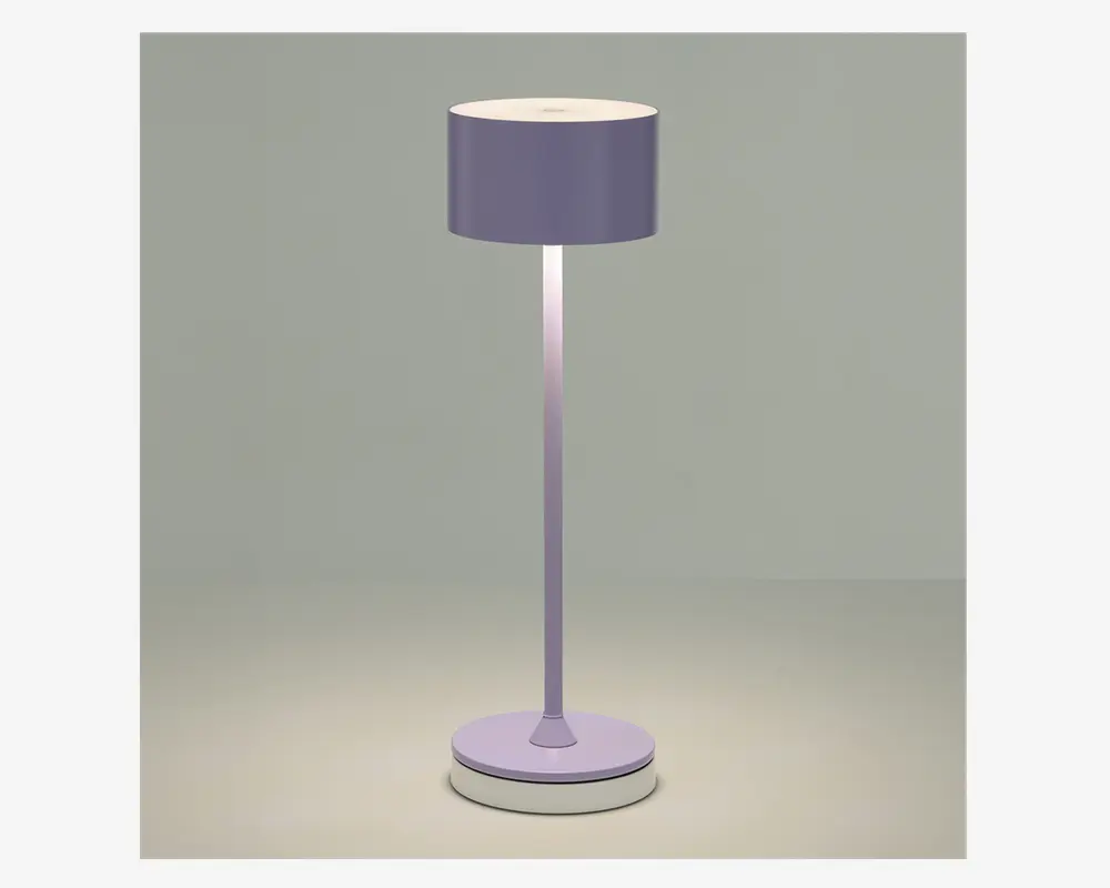 Høj gulvlampe med en cylindrisk lampeskærm i en afdæmpet lavendelfarve. Lampen har en slank, lige stang og en rund, solid fod, som begge matcher skærmens farve. Designet er minimalistisk og moderne, og lampen udsender et blødt, diffust lys fra toppen og bunden af skærmen.