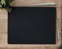 Et sæt rektangulære dækkeservietter med afrundede hjørner, vist stablet på en træoverflade. Den øverste dækkeserviet er ensfarvet sort, mens de underliggende har afdæmpede farver som blågrøn, brun og lysegrå. Dækkeservietterne har en glat, mat overflade og ser ud til at være lavet af et fleksibelt materiale, der beskytter bordet.