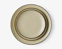Sæt med to runde tallerkener i en lys beige farve med blank overflade. Hver tallerken har et enkelt, elegant design med en tynd mørk kant langs kanten, hvilket giver et klassisk og tidløst udtryk. Tallerkenerne er stablet, så størrelsesforskellen er synlig.