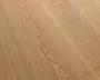Nærbillede af en lys egetræsoverflade med varme beige-brune toner og tydelige naturlige åretegninger, der løber diagonalt.