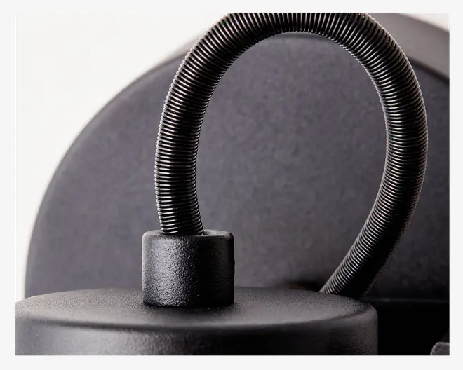 Nærbillede af en fleksibel, rillet sort metal-gåsehals, der er fastgjort til en mat sort base. Overfladen har en let tekstureret finish, og gåsehalsen gør det muligt at justere positionen.