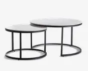 Sæt med to runde indskudsborde med hvide bordplader i marmorlook og slanke sorte metalstel. Det største bord er lidt højere og bredere, så det mindre bord kan skubbes delvist ind under for pladsbesparende opbevaring. Begge borde har et minimalistisk, moderne design med åbne, cirkulære baser, der giver et let og luftigt udtryk.