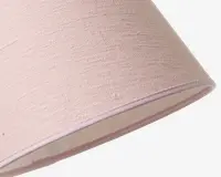 Nærbillede af en lampeskærm med lyserødt stof på ydersiden. Stoffet har en diskret tekstureret vævning, hvilket giver et let rustikt og hyggeligt udtryk. Lampeskærmen har en klassisk konisk tromleform med pænt afsluttede kanter og en lys indvendig foring.