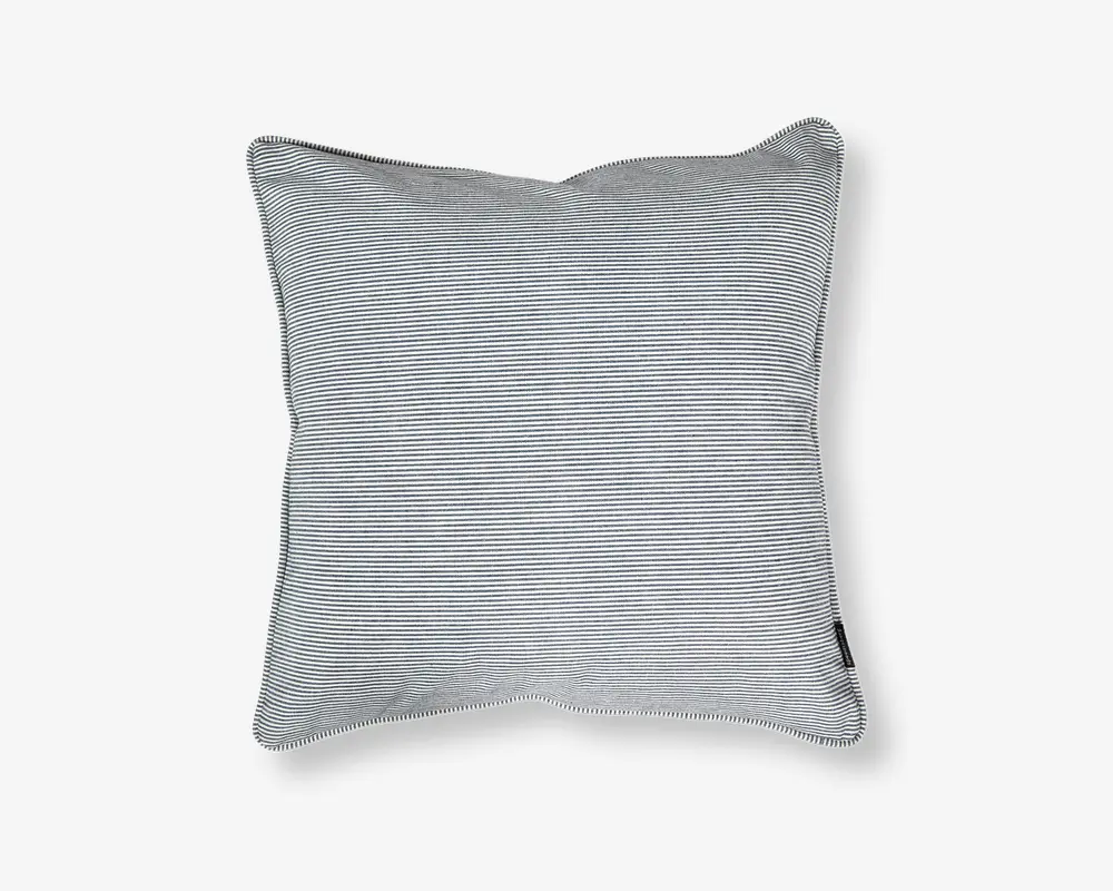 Rektangulær pude med betræk i tynde, horisontale sorte og hvide striber. Stoffet ser blødt og glat ud med pænt syede kanter og et lille stofmærke i den ene side. Puden fremstår fyldig og støttende, velegnet til brug på sofa eller seng.