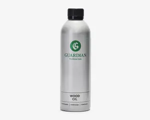 En høj, cylindrisk sølvfarvet flaske med sort skruelåg. Flasken har et grønt logo og mærket 'Guardian Furniture Care' trykt på forsiden. Nederst på etiketten står der tydeligt 'Wood Oil' og oversættelser på flere sprog. Designet er stilrent og moderne med en mat metallisk overflade.