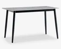 Rektangulært bord med en lysegrå bordplade med marmoreffekt og fire slanke, sorte metalben, der er let skråtstillede. Designet er minimalistisk og moderne med en glat overflade og rene linjer, velegnet til spise- eller kontorbrug.