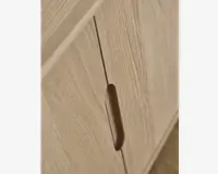 Nærbillede af en skabslåge lavet af lyst træ med naturligt åremønster. Lågen har et lodret, indfældet greb, der er udskåret direkte i træet for et minimalistisk og moderne udtryk. Kanterne er glatte, og overfladen fremstår mat.