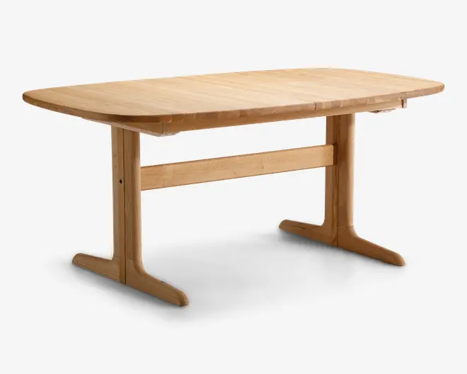 Rektangulært bord i lyst træ med en glat overflade. Bordpladen har blødt afrundede kanter og hjørner. Bordet står på to solide, T-formede ben, der er forbundet med en tværgående bjælke for ekstra stabilitet. Designet er minimalistisk og funktionelt med fokus på træets naturlige årer.