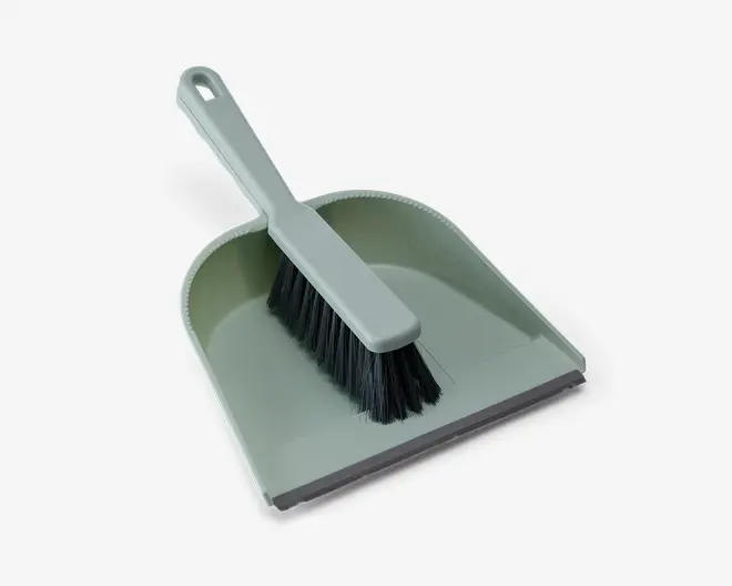 Et lysegråt fejebakke- og kostesæt. Fejebakken har en bred, flad bund med let hævede sider og bagkant, som hjælper med at holde snavset inde. Foran har fejebakken en gummikant, der sikrer tæt kontakt med gulvet og gør det nemmere at feje støv og snavs op. Kosten har et matchende lysegråt håndtag og tætte sorte børstehår, der er effektive til fejning. Kosten kan placeres inde i fejebakken for nem og kompakt opbevaring.