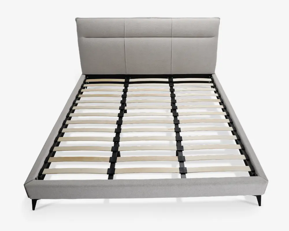 Moderne sengegavl med lysegråt polstret hovedgærde, der har tre store rektangulære paneler. Rammen har en lav profil med matchende gråt stof på siderne og fodenden. Bunden består af jævnt fordelte lameller i træ, som understøttes af en sort metalstruktur, hvilket gør det muligt at bruge sengen uden boxmadras. Sengen står på korte, skrå sorte ben.