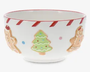 Hvid keramikskål med hævede festlige motiver, herunder et grønt juletræ med farvede prikker og honningkagefigurer. Skålens kant er dekoreret med et rød- og hvidstribet slikstokmønster. Skålen har en blank overflade og en rund form.