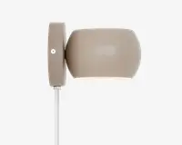 En moderne vægmonteret lampe med en glat, mat taupe-farvet overflade. Lampen har en ovalt formet skærm, der leder lyset nedad, samt en rektangulær vægplade med en synlig skrue til montering. En hvid ledning går ud fra bunden af vægpladen. Designet er minimalistisk og moderne, velegnet til forskellige indretninger.