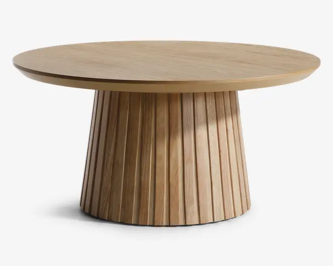 Rundt bord med en glat, flad træbordplade og en bred, rillet sokkel. Soklen har lodrette riller, der giver struktur og et spændende udtryk. Den naturlige træfinish giver et varmt og moderne udseende.