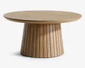 Rundt bord med en glat, flad træbordplade og en bred, rillet sokkel. Soklen har lodrette riller, der giver struktur og et spændende udtryk. Den naturlige træfinish giver et varmt og moderne udseende.