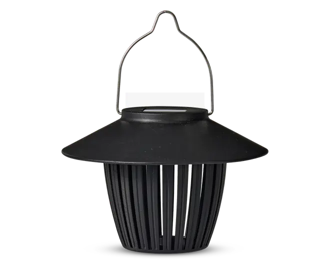 Sort lanterne-lignende enhed med bred, skrånende top og lodrette lameller, der udgør kroppen. Den har et buet metalhåndtag til ophængning og en mat overflade. Designet giver luftgennemstrømning gennem lamellerne, og toppen beskytter ovenfra.