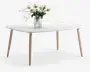 Rektangulært bord med en glat, mat hvid bordplade og fire skråtstillede ben i lyst træ. Bordet har et minimalistisk, moderne design. Midt på bordet står en rillet glasvase med en buket lyserøde og cremefarvede roser samt grønt løv.