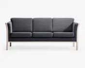 Mod embedded tre-personers sofa med mørkegr exc stofpolstring, der har tre separate sæde- og ryghynder for ekstra komfort. Sofaen har et minimalistisk design med lyse træarmlæn og ben, hvilket skaber en stilfuld kontrast til det mørke stof. Armlænene er let buede, trial sofaen fremstår elegant og moderne.