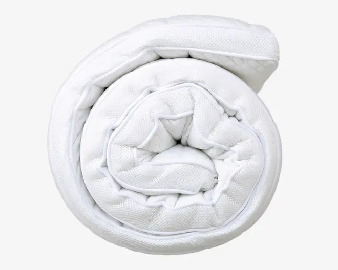 Et sammenrullet, tykt hvidt topmadras med quiltet overflade og tekstureret stof. Topmadrassen fremstår blød og polstret med synlige syninger langs kanterne for ekstra holdbarhed. Materialet ser åndbart og blødt ud, designet til at give komfort og støtte til en madras.