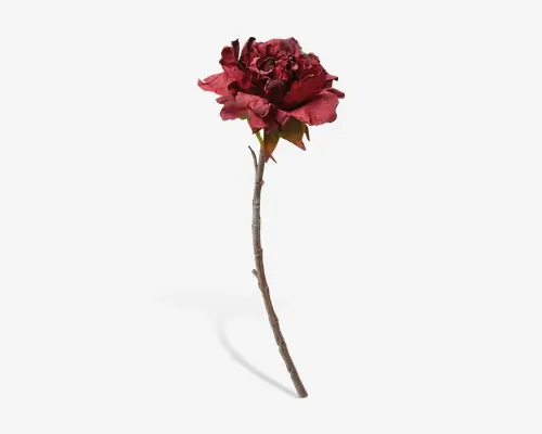 En enkelt kunstig blomsterstilk med en mørkerød pæon i fuldt flor, der har lagdelte, let krøllede kronblade. Stilken er lang og slank med en naturlig brun farve, og der ses et par grønne blade ved blomsterhovedets base. Kronbladene har en realistisk tekstur og diskrete farvevariationer, hvilket giver blomsten et naturtro udseende.