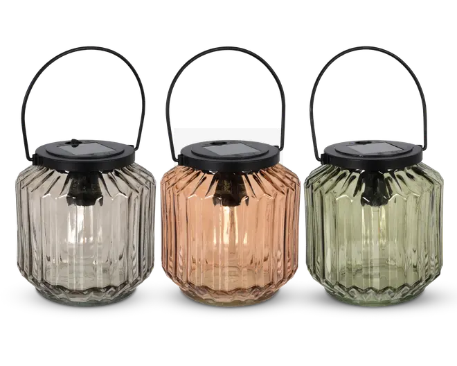 Sæt med tre lanterner med riflede glaslegemer i klar, ravfarvet og lysegrøn. Hver lanterne har et sort metalhåndtag og et sort låg med solcellepanel på toppen, velegnet til udendørs brug. Glasset er facetteret for et dekorativt udseende, og lanternerne er designet til at være bærbare og nemme at hænge op.