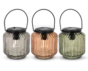 Sæt med tre lanterner med riflede glaslegemer i klar, ravfarvet og lysegrøn. Hver lanterne har et sort metalhåndtag og et sort låg med solcellepanel på toppen, velegnet til udendørs brug. Glasset er facetteret for et dekorativt udseende, og lanternerne er designet til at være bærbare og nemme at hænge op.