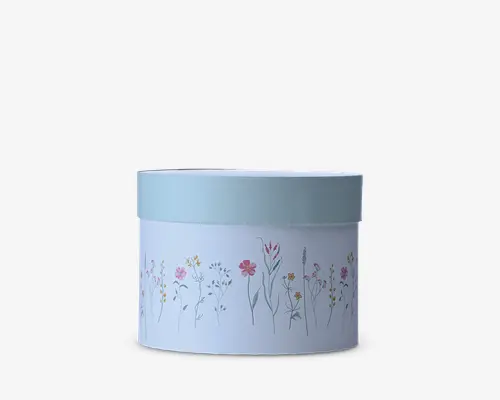 En lyseblå cylindrisk beholder med matchende låg, dekoreret hele vejen rundt med et fint blomstermønster i bløde rosa, gule og grå nuancer.