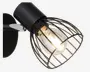 En vægmonteret lampe med mat sort finish. Lampen har en cylindrisk base og en synlig pære omgivet af et sort metalgitter, hvilket giver et industrielt og moderne udtryk. Pæren er synlig og udsender et varmt lys, og lampen er fastgjort til en rund vægplade.