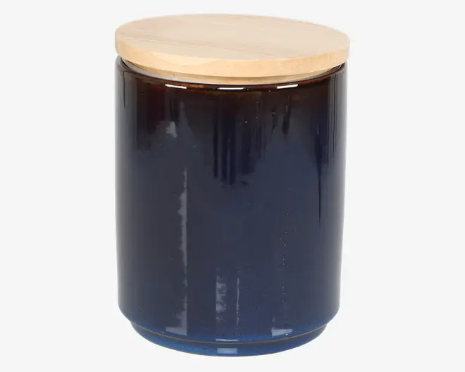 En cylindrisk, mørkeblå glasbeholder med glat overflade og et fladt, rundt låg af lyst træ. Låget sidder tæt og giver en lufttæt lukning. Beholderen har et minimalistisk design, der passer godt til moderne køkkener eller opbevaringsområder.