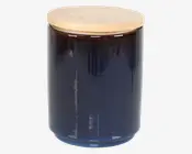 En cylindrisk, mørkeblå glasbeholder med glat overflade og et fladt, rundt låg af lyst træ. Låget sidder tæt og giver en lufttæt lukning. Beholderen har et minimalistisk design, der passer godt til moderne køkkener eller opbevaringsområder.