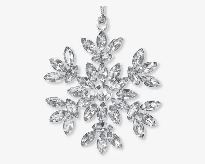 Pynt formet som en snefnug, bestående af flere klare, marquise-slebne krystaller arrangeret i et symmetrisk, udstrålende mønster. Krystallerne er sat i en ramme af sølvfarvet metal, hvilket giver et funklende og elegant udseende. Et lille øje i toppen gør det nemt at hænge op.