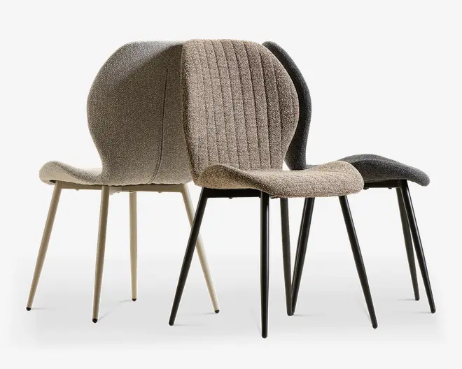 Et sæt polstrede spisebordsstole med afrundede rygge, teksturerede stofsæder og slanke, tilspidsede metalben i neutrale beige og mørkegrå nuancer.