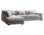 Moderne hjørnesofa i lysegråt stof med venstrevendt chaiselong. Sofaen har brede, firkantede armlæn, dybe sædehynder og fem matchende ryghynder for ekstra komfort. Betrækket har en diskret tekstureret vævning, og sofaen står på lave, sorte blokformede ben.