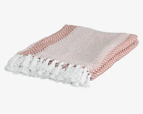 Blødt vævet tekstil med et diskret lyserødt og hvidt mønster, der har sildebensdesign langs kanterne. Stoffet har en tekstureret overflade og afsluttes med lange, hvide frynser i enderne, hvilket giver et dekorativt udtryk.