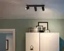 Sort loftspot med tre lyskilder, smal rektangulær monteringsskinne og tre justerbare cylindriske spotlamper, hvor den ene peger udad og de to andre er vinklet nedad.