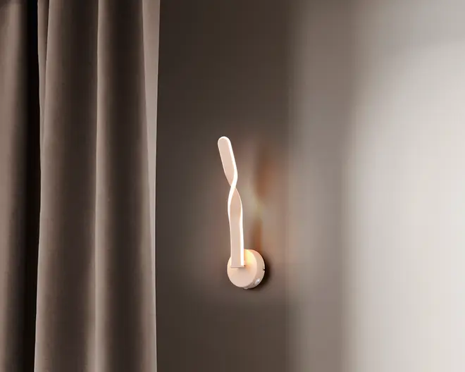 Væghængt lampe med et moderne, skulpturelt design, der har en snoet, aflang LED-stav i mat hvid finish. Lampen er monteret på en rund base og udsender et blødt, varmt lys, som skaber en elegant stemning på væggen. Velegnet til moderne indretning.
