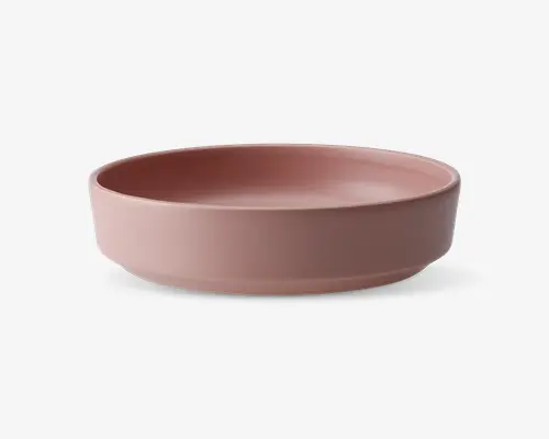 En rund, lav skål med glat mat finish i en afdæmpet rosa farve. Skålen har lige sider og en flad bund, hvilket giver et moderne og minimalistisk udtryk. Der er ingen synlige mønstre eller dekorationer.