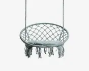 Rund hængestol med flettet macramé-design, robust cirkulær ramme og en blød, polstret sædehynde. Stolen hænger i to reb og er pyntet med lange, dekorative frynser langs den nederste kant. Ryglænet har et åbent gittermønster, som giver både støtte og ventilation.