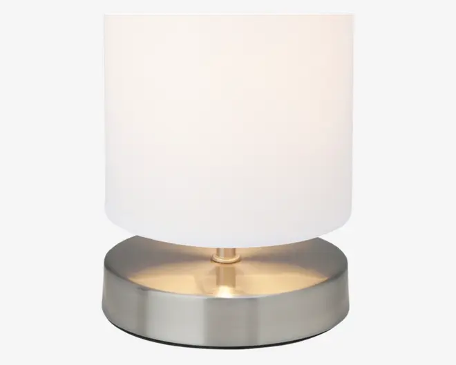 En moderne bordlampe med en cylindrisk hvid stofskærm og en rund fod i børstet metal med en diskret guldfarvet detalje i midten. Lampen har et minimalistisk og stilrent design, der passer til moderne indretning.