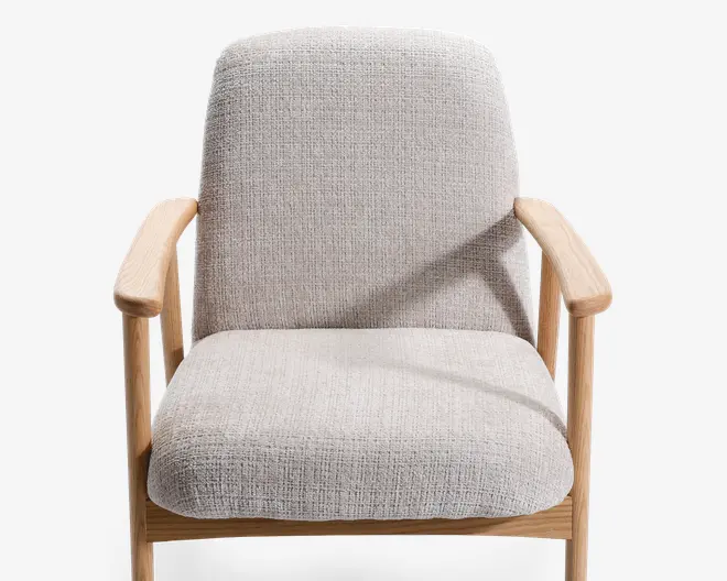 Stol med lysebeige, tekstureret stofpolstring på sæde og ryglæn. Stellet, inklusive armlæn og ben, er lavet af lyst træ med en glat finish. Armlænene er let buede for komfort, og det samlede design er minimalistisk og moderne med fokus på rene linjer og naturlige materialer.