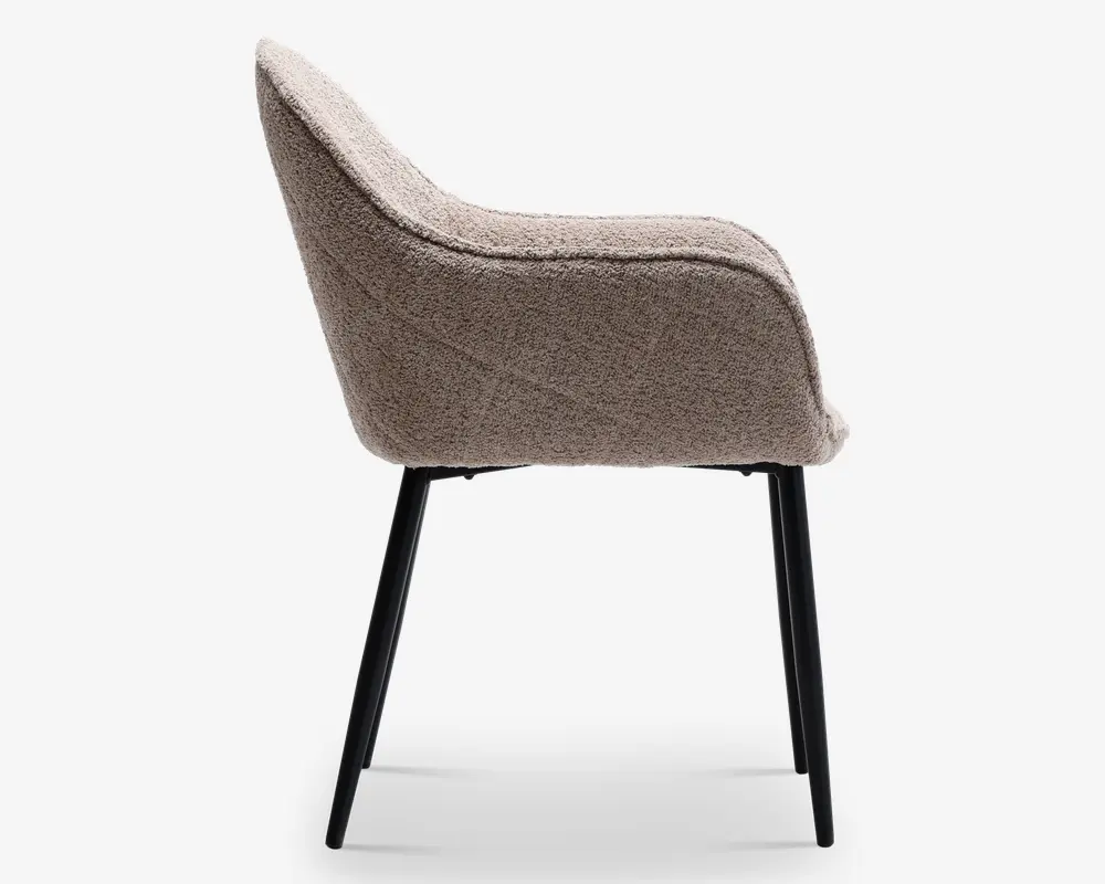 Sidevisning af en moderne stol med buet ryglæn og sæde, polstret med et tekstureret, taupefarvet stof. Stolen har slanke, skråtstillede sorte metalben, hvilket giver den et stilrent og moderne udtryk.