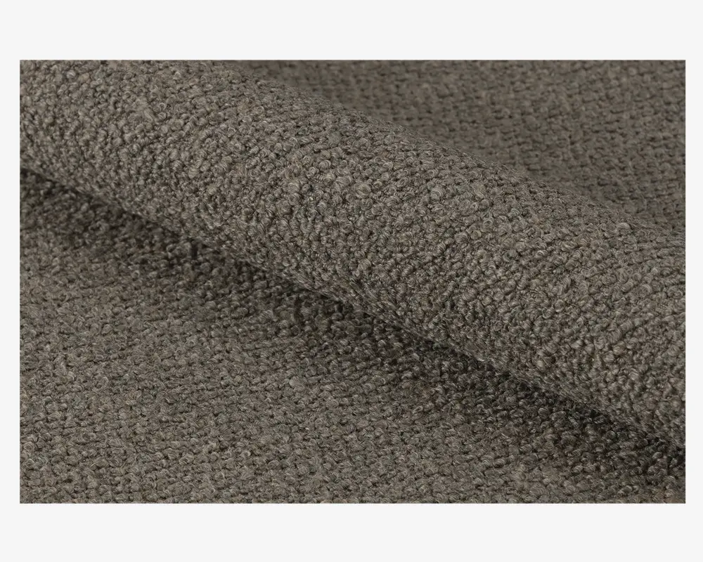 Nærbillede af et tekstiler med en tæt vævet, løkket overflade i en dæmpet brungrå farve, som giver et blødt og nubret udtryk. Materialet ser tykt og slidstærkt ud, velegnet til polstring eller kraftig brug.