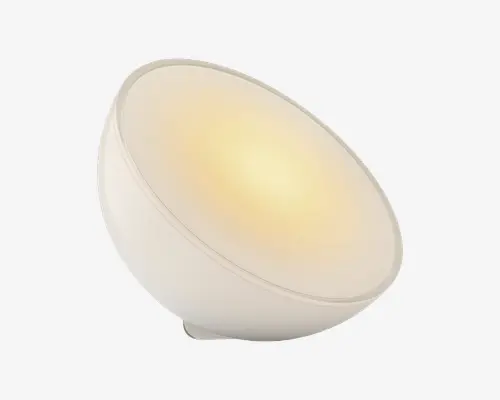En moderne, kuppelformet lampe med en glat, mat hvid overflade. Lampen er vinklet opad og udsender et varmt, diffust lys fra dens brede, cirkulære front. Det minimalistiske design har rene linjer og en ensartet overflade, hvilket gør den velegnet til moderne indretning.