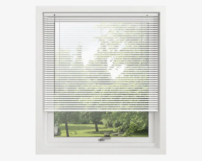 Hvide vandrette lamelgardiner, der er delvist trukket ned foran et vindue, så lyset filtreres ind. Lamellerne er jævnt fordelt og lavet af et let materiale, hvilket giver privatliv, men stadig tillader noget udsyn. Vinduesrammen er hvid, og gardinet har et rent, moderne udseende.