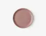 En rund, flad tallerken med en glat, mat overflade i en afdæmpet støvet rosa farve. Tallerkenen har en let hævet kant og et minimalistisk, moderne design uden mønstre eller dekorationer.
