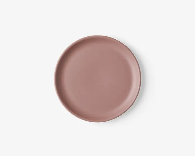 En rund, flad tallerken med en glat, mat overflade i en afdæmpet støvet rosa farve. Tallerkenen har en let hævet kant og et minimalistisk, moderne design uden mønstre eller dekorationer.