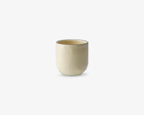 En minimalistisk, cylindrisk kop med en glat, mat cremefarvet overflade. Koppen har en afrundet bund og lige sider samt en diskret, tynd mørk kant øverst. Designet er enkelt og moderne uden hank eller yderligere dekoration.