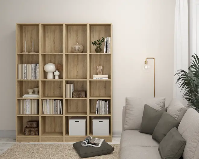 Høj reol i lyst træ med naturlig finish, bestående af fire kolonner og fem rækker af åbne, kvadratiske rum. Hylderne er fyldt med en blanding af bøger, dekorative genstande som vaser, en lille potteplante, en fletkurv og to hvide opbevaringskasser. Designet er minimalistisk og moderne, velegnet til organisering og udstilling af ting i stuen.