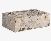 Rektangulær æske med hængslet låg, dekoreret med et elegant blomstermønster i nuancer af creme, beige og brun. Overfladen er prydet med detaljerede illustrationer af store blomstrende blomster og blade, hvilket giver et vintage og sofistikeret udtryk. Æsken har skarpe kanter og en glat finish, velegnet til dekoration eller opbevaring.