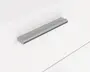 Elegant, moderne skuffegreb med børstet metalfinish. Grebet har en lige, aflang form med afrundede kanter og en let buet overflade for et behageligt greb. Det er monteret vandret på en flad, hvid skuffefront og giver et minimalistisk og nutidigt udtryk.