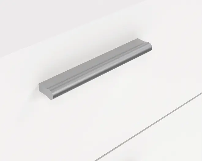 Elegant, moderne skuffegreb med børstet metalfinish. Grebet har en lige, aflang form med afrundede kanter og en let buet overflade for et behageligt greb. Det er monteret vandret på en flad, hvid skuffefront og giver et minimalistisk og nutidigt udtryk.